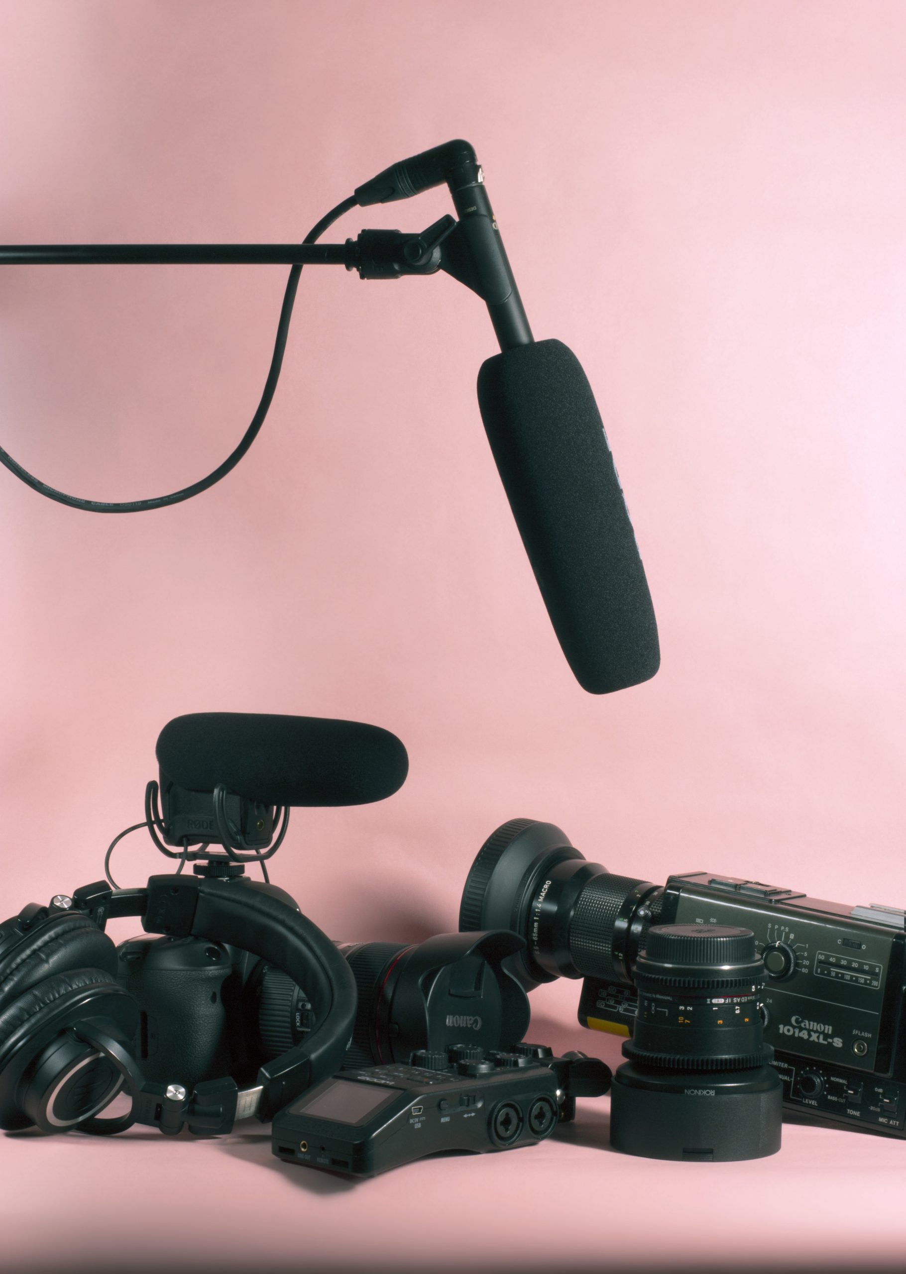 A heap of video and audio equipment in front of a pink backdrop